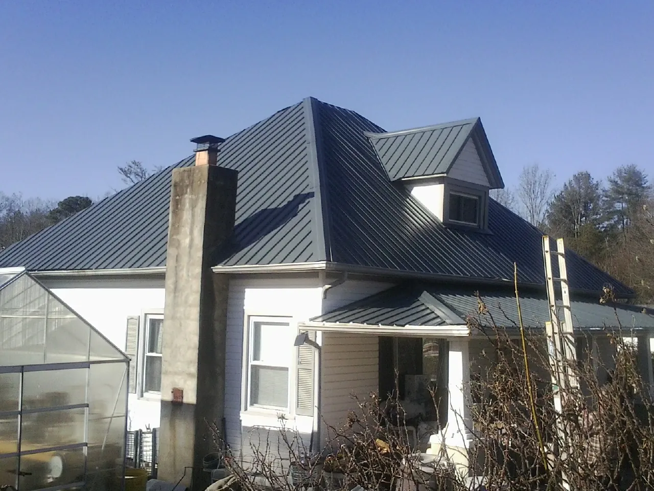 Dark blue standing seam metal roof on a white farmhouse with dormer — Slate & Tile Roof Repair by Roofing Brothers in Laurys Station
