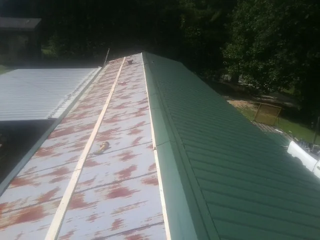Old rusted panels beside newly installed green metal roofing — Wind Damage Roof Repair by Roofing Brothers in Laurys Station