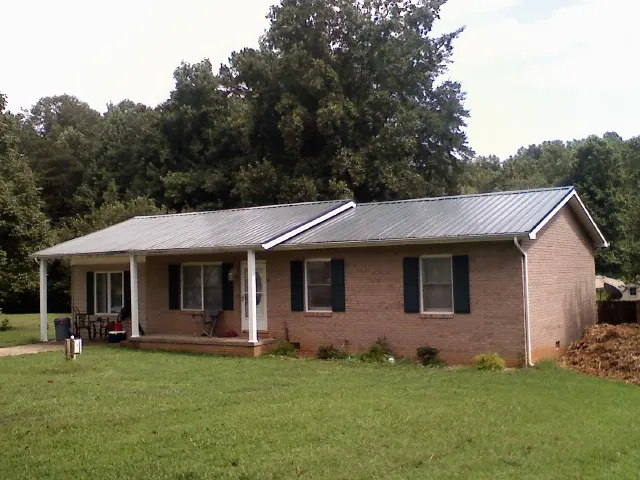 Gray metal roof on a brick ranch house with a side carport in Laurys Station