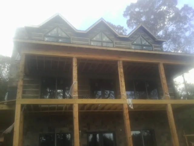 Dormers and porch framing on a large log home under construction — Roof Coating work by our crew in Laurys Station