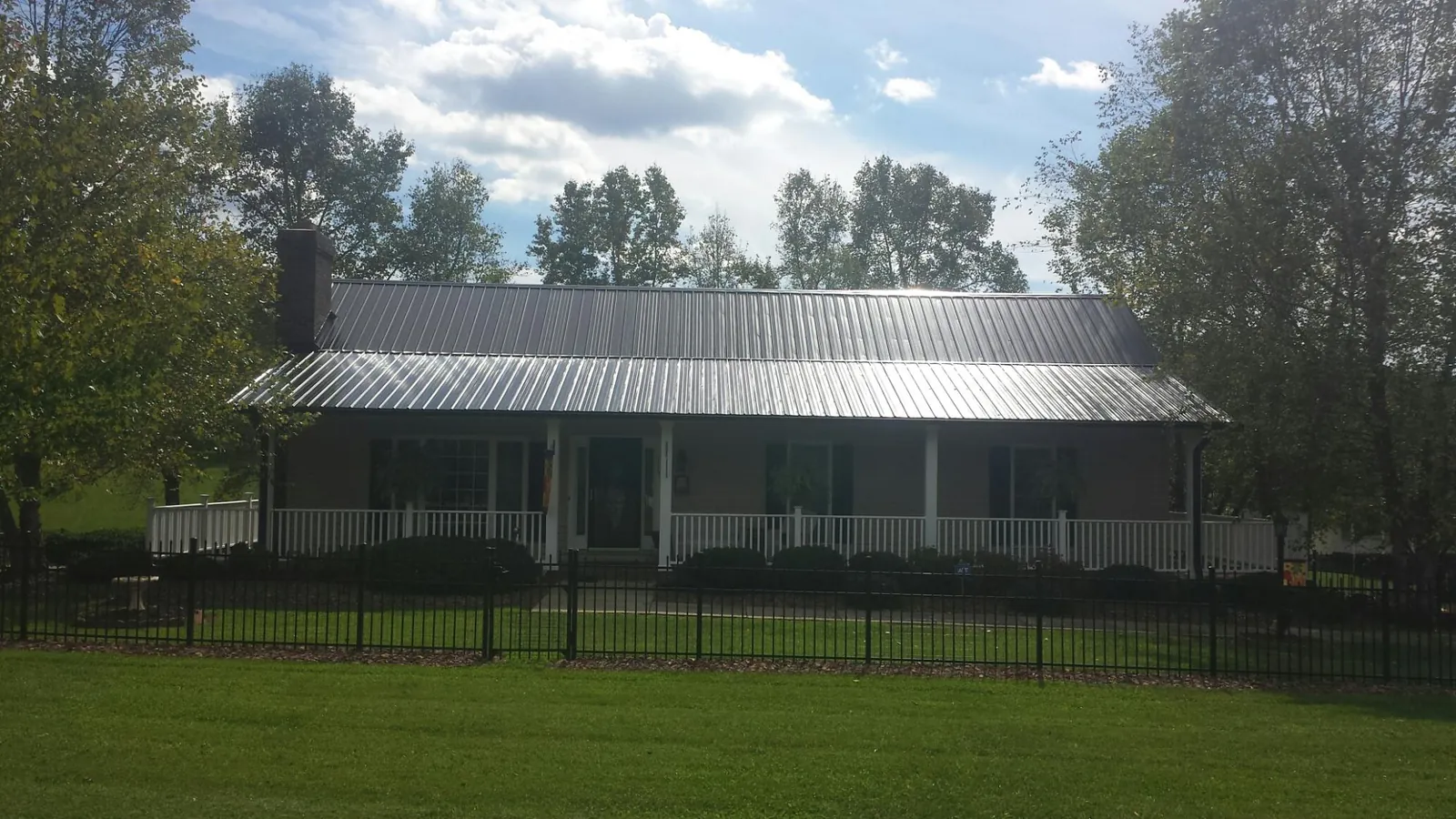 Gray metal roof on a brick ranch with a full width front porch — Gutter Guard Installation work by our crew in Laurys Station