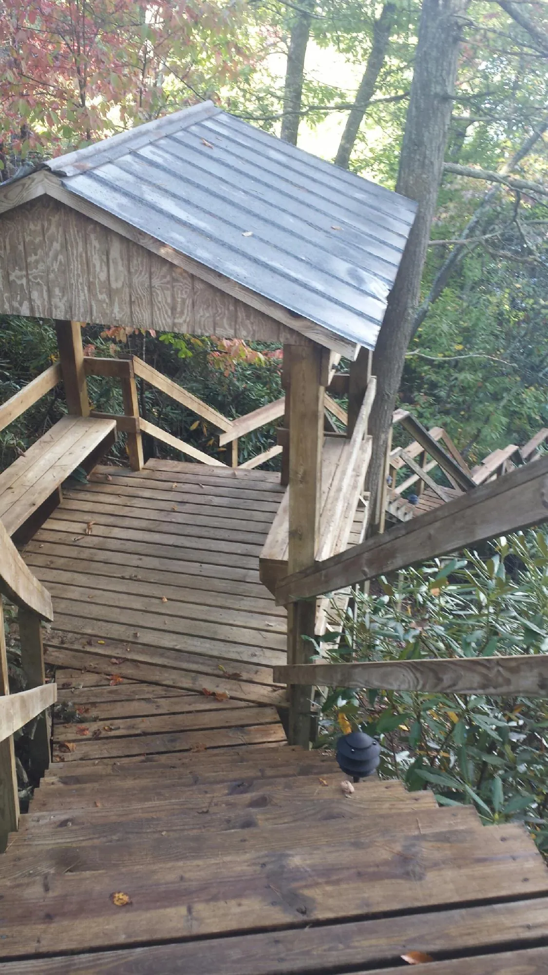 Metal roofed shelter over wooden steps on a wooded walkway — Skylight Repair & Installation work by our crew in Laurys Station