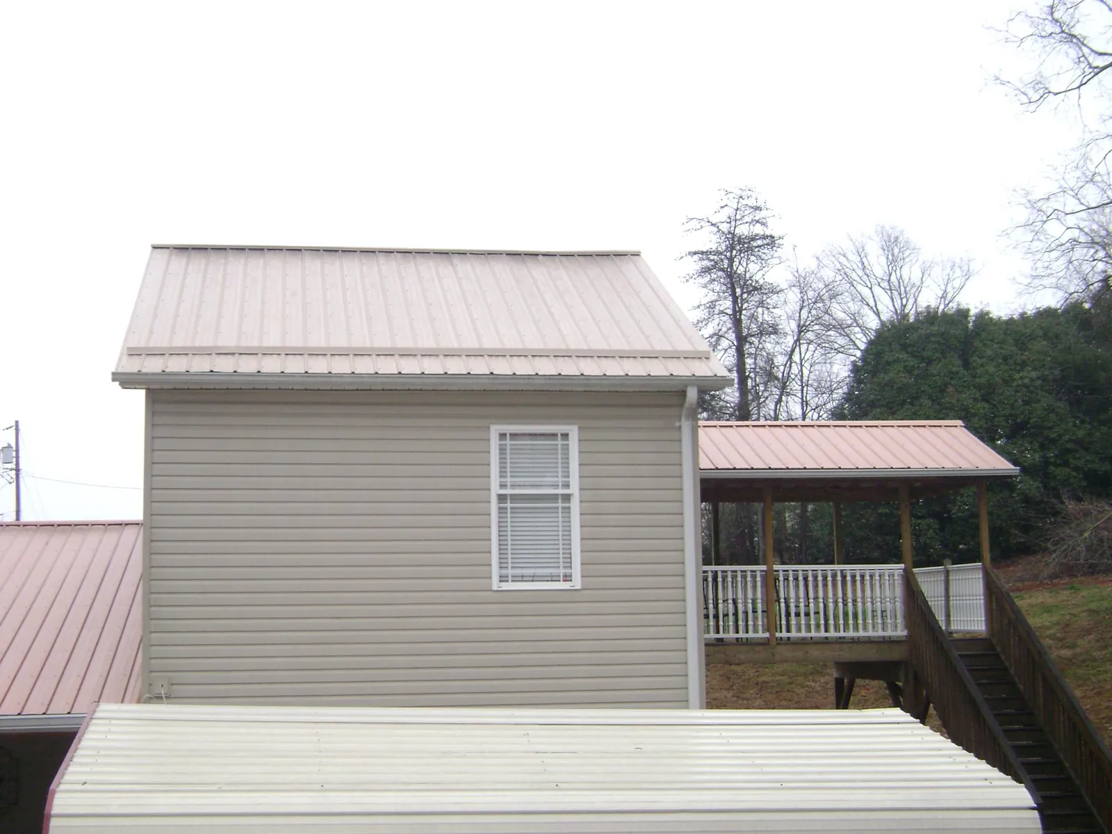 Tan metal roofs on a two story addition and attached porch, from a Roof Replacement job in Laurys Station