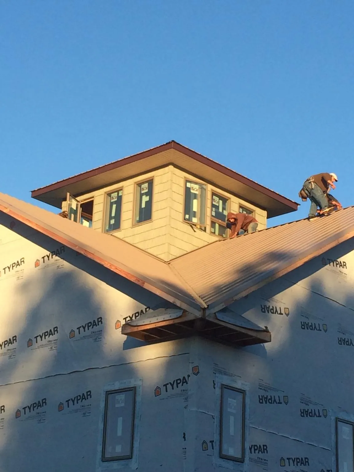 Roofers working around a rooftop cupola on a new metal roof at sunset — Roof Waterproofing in Laurys Station by Roofing Brothers